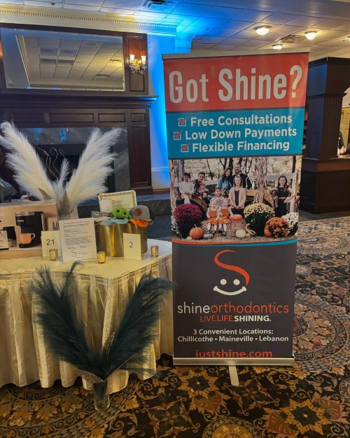 Table with gift bags and raffle items with a banner for shine orthodontics